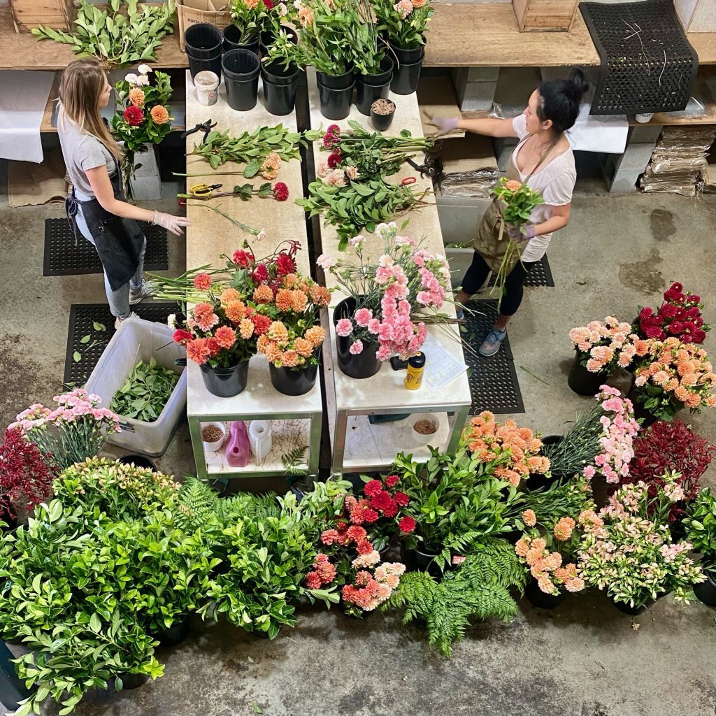 Two florists arranging a large selection of vibrant flowers