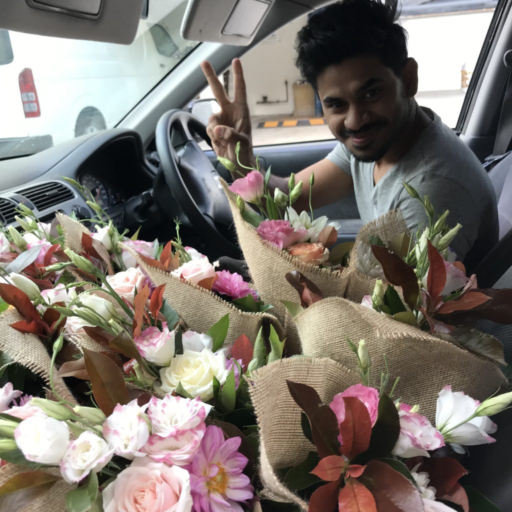 Flower delivery driver in Sydney holding multiple bouquets in car